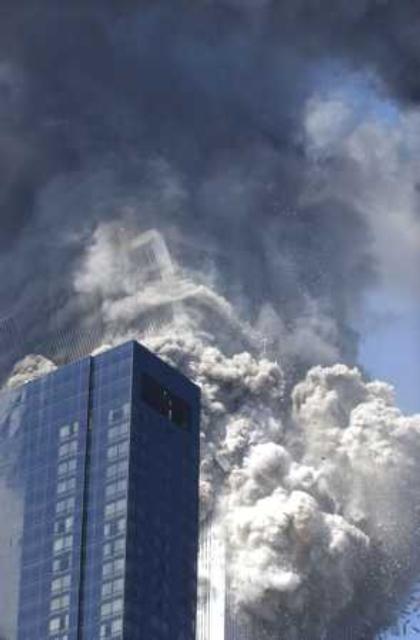 Figure 26. (9/11/2001) WTC2 top block continuing to tilt and beginning to lose structural coherence, transitioning from solid to particulate
  <br>
  - Photo by Amy Sancetta/AP